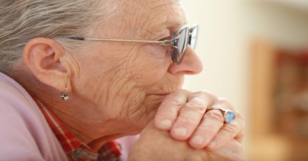 Side image of elderly woman with face on hands